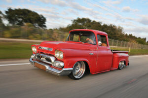 Custom red 1958 GMC 100 running on the highway