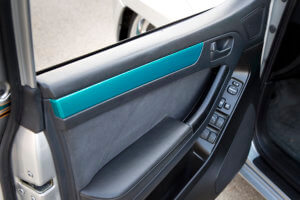 Interior door panel with teal accent.