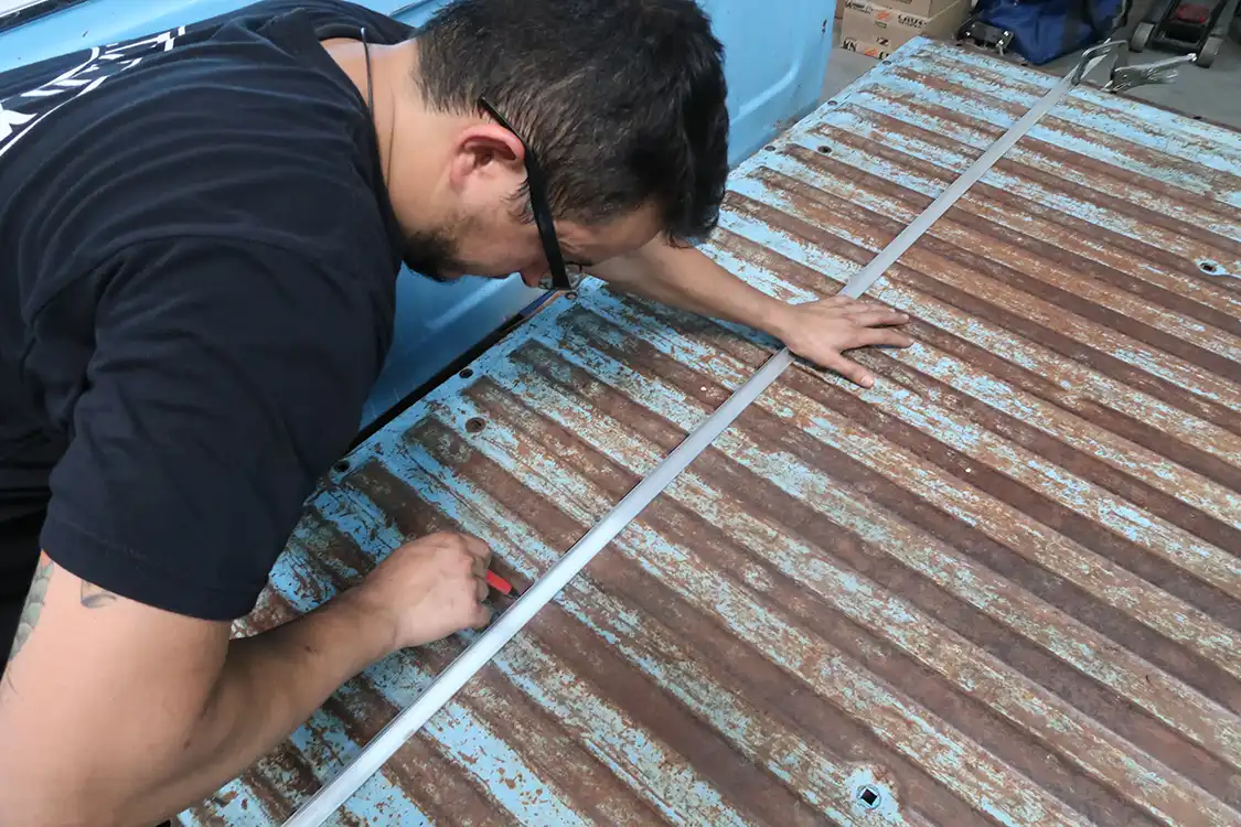 Moving to the front of the bed, Kyle marks out 12 inches to remove from the floor, then cuts it off